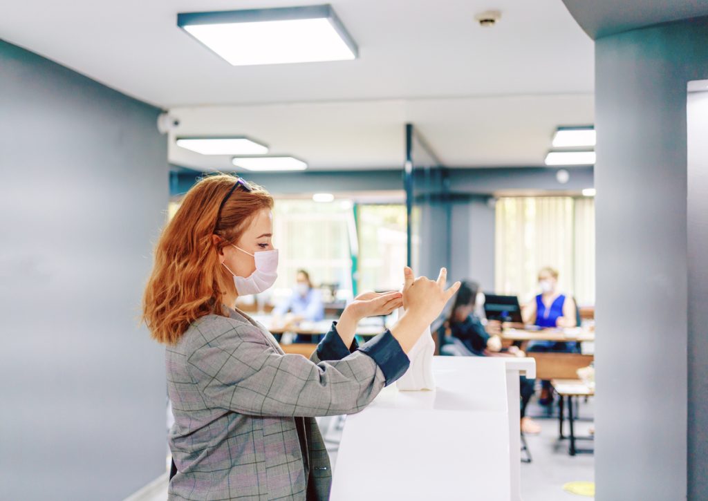 Business woman cleaning hands with sanitizer in the office