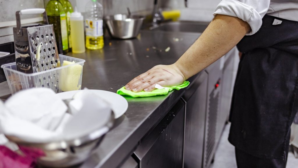 Waiter wiping the counter top in the commercial kitchen