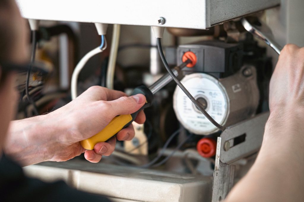 A man is repairing a water-heating boiler, close-up.