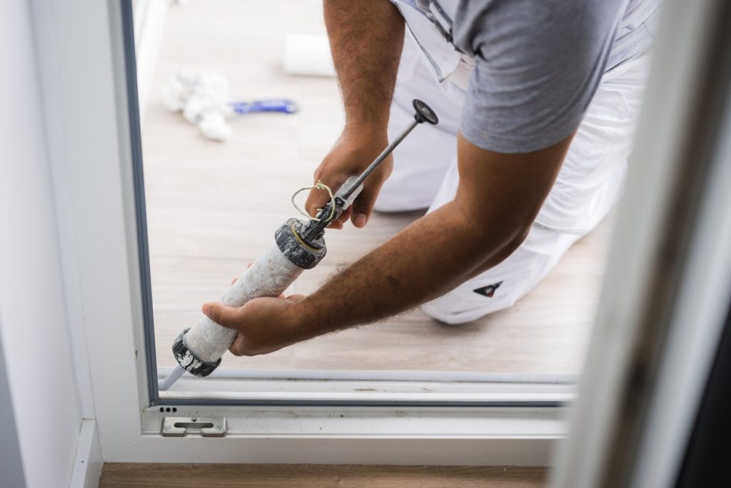 Construction worker using a silicone sealant gun, close-up